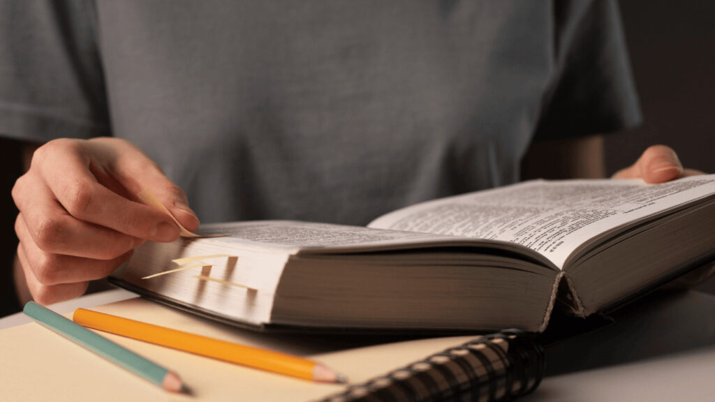 A person annotating a book´with tabs. 