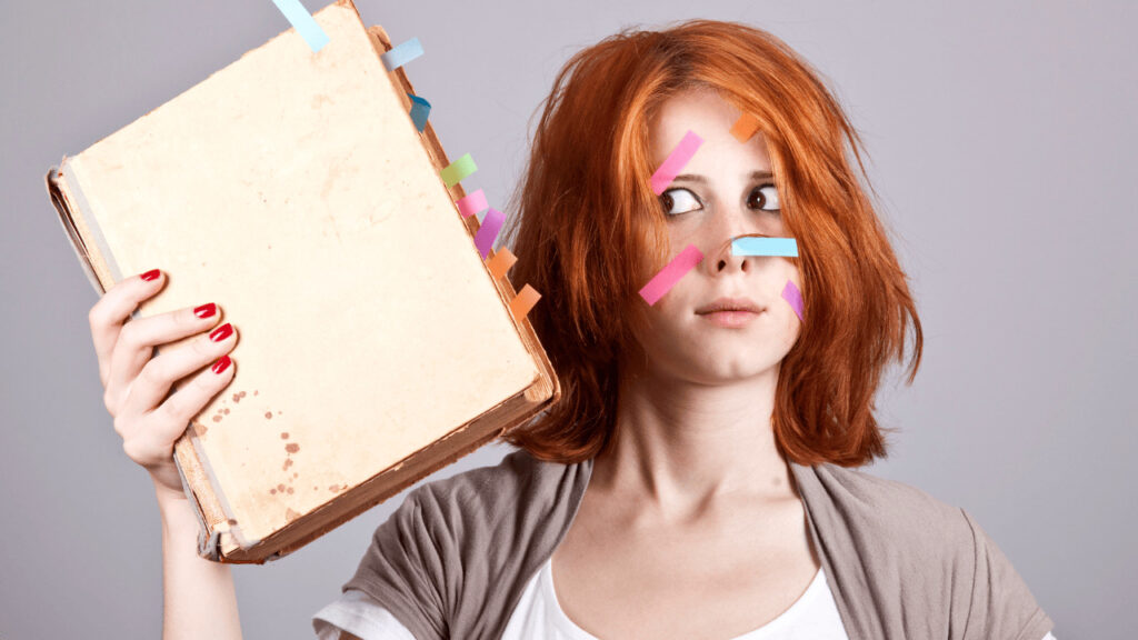 A girl holding a book annotated with colorful tabs.